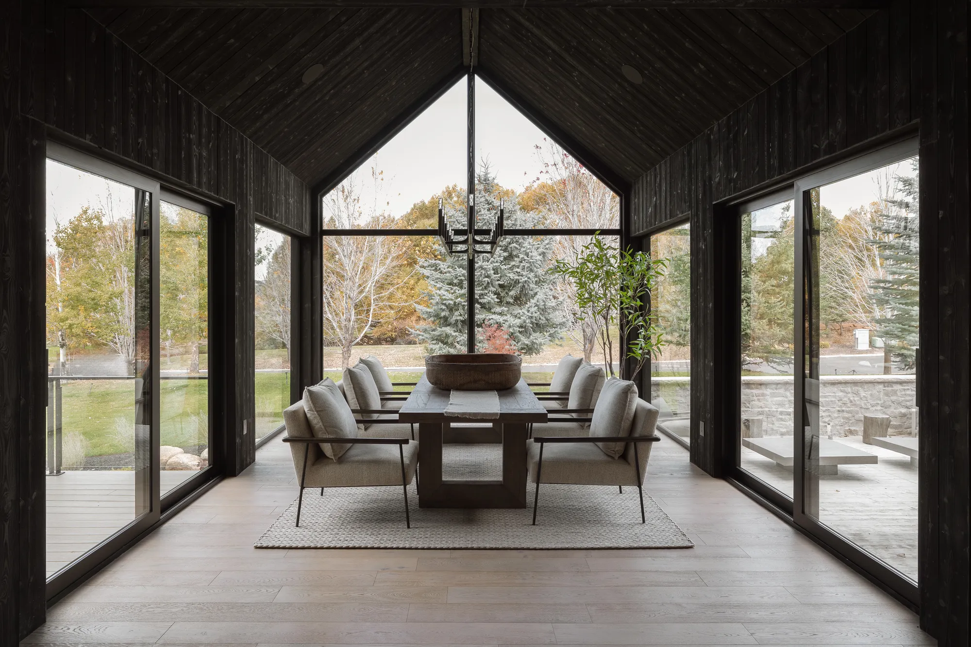 Charred-timber glass dining pavilion with gable window wall and fall foliage