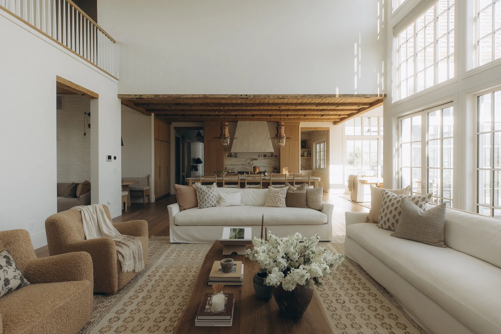 Two-story great room with a wall of divided-light windows and beamed ceiling