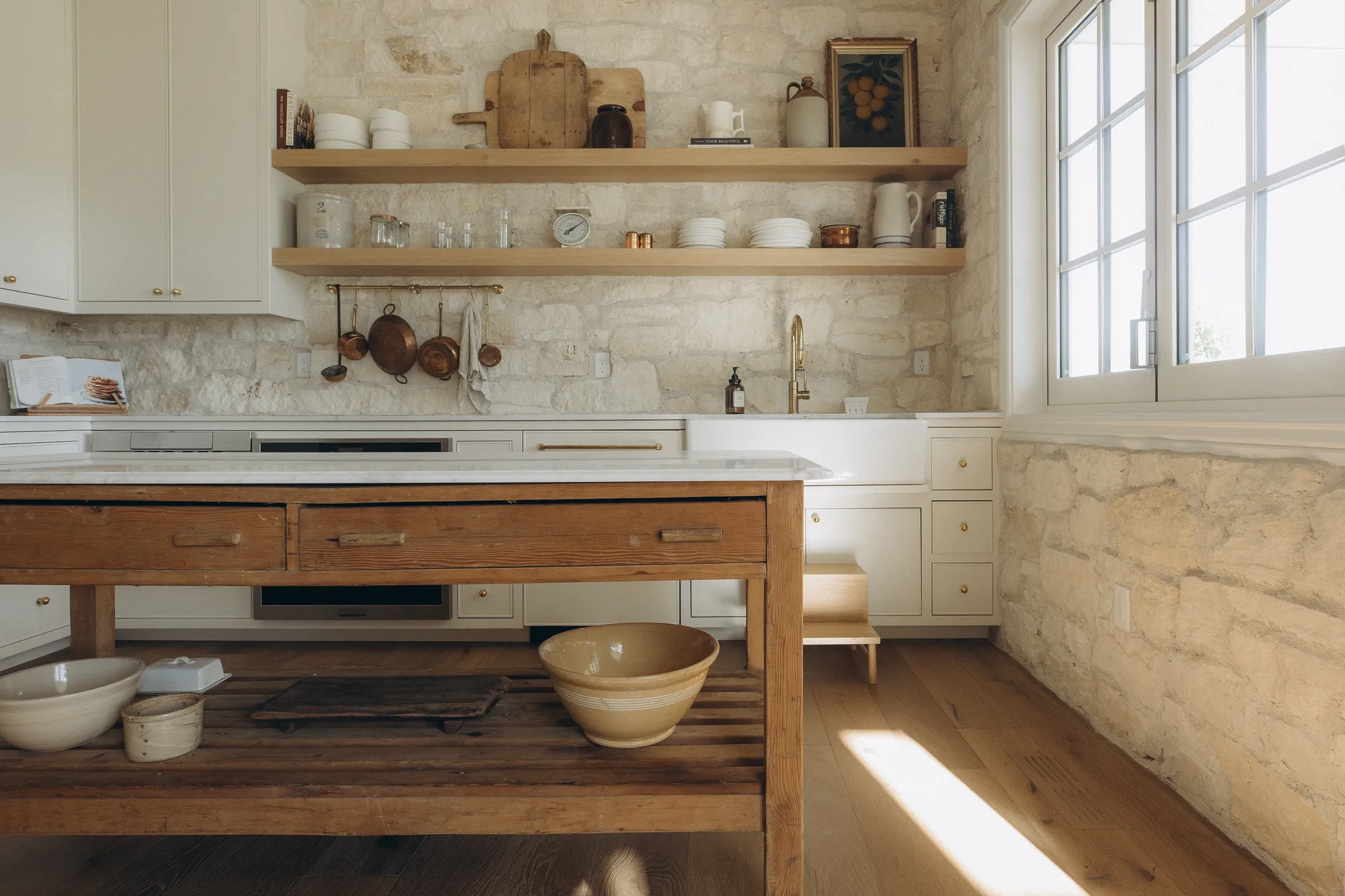 European farmhouse kitchen with antique wood island and limestone walls