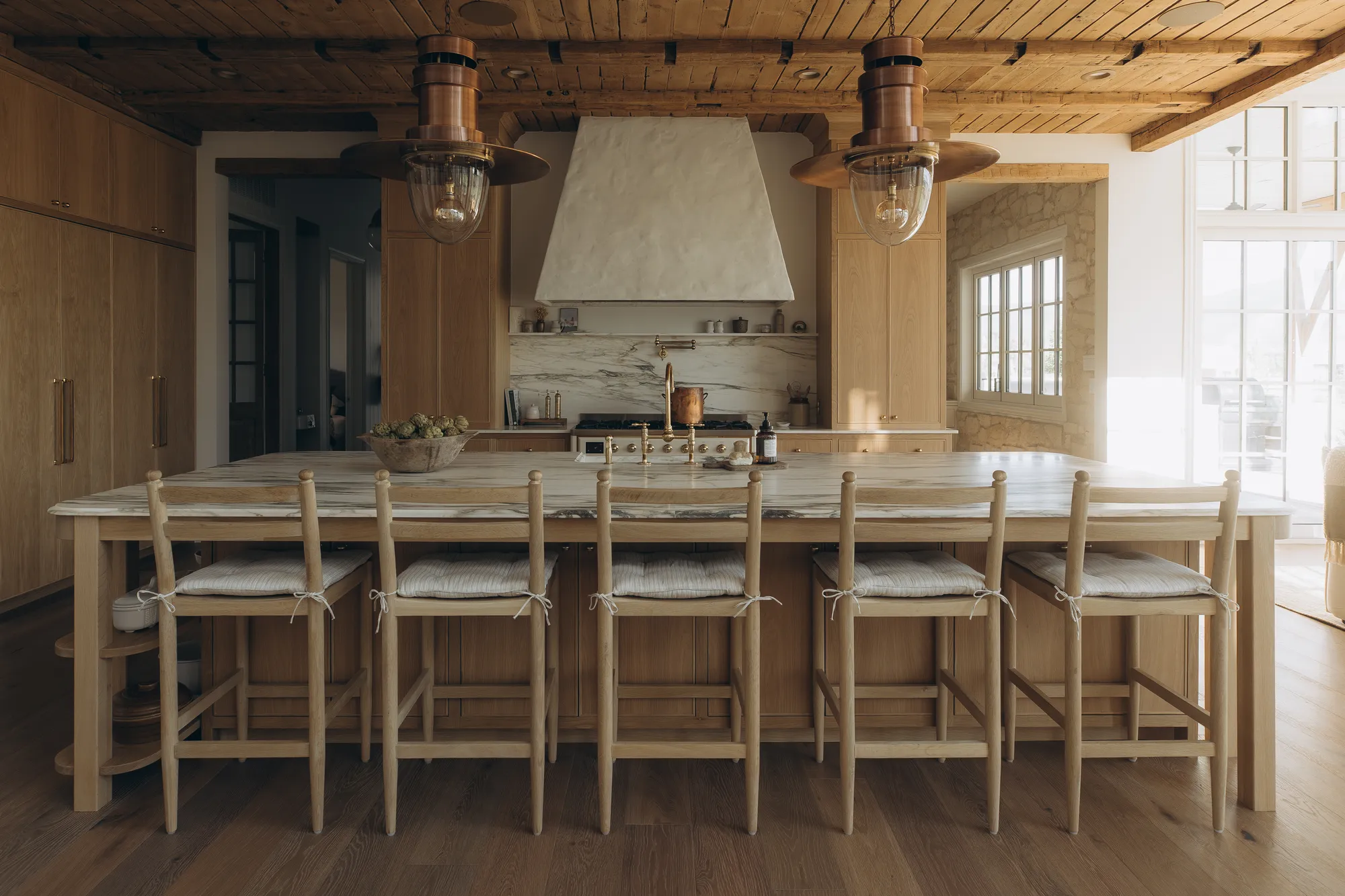 Warm oak kitchen with marble island and copper lantern pendants