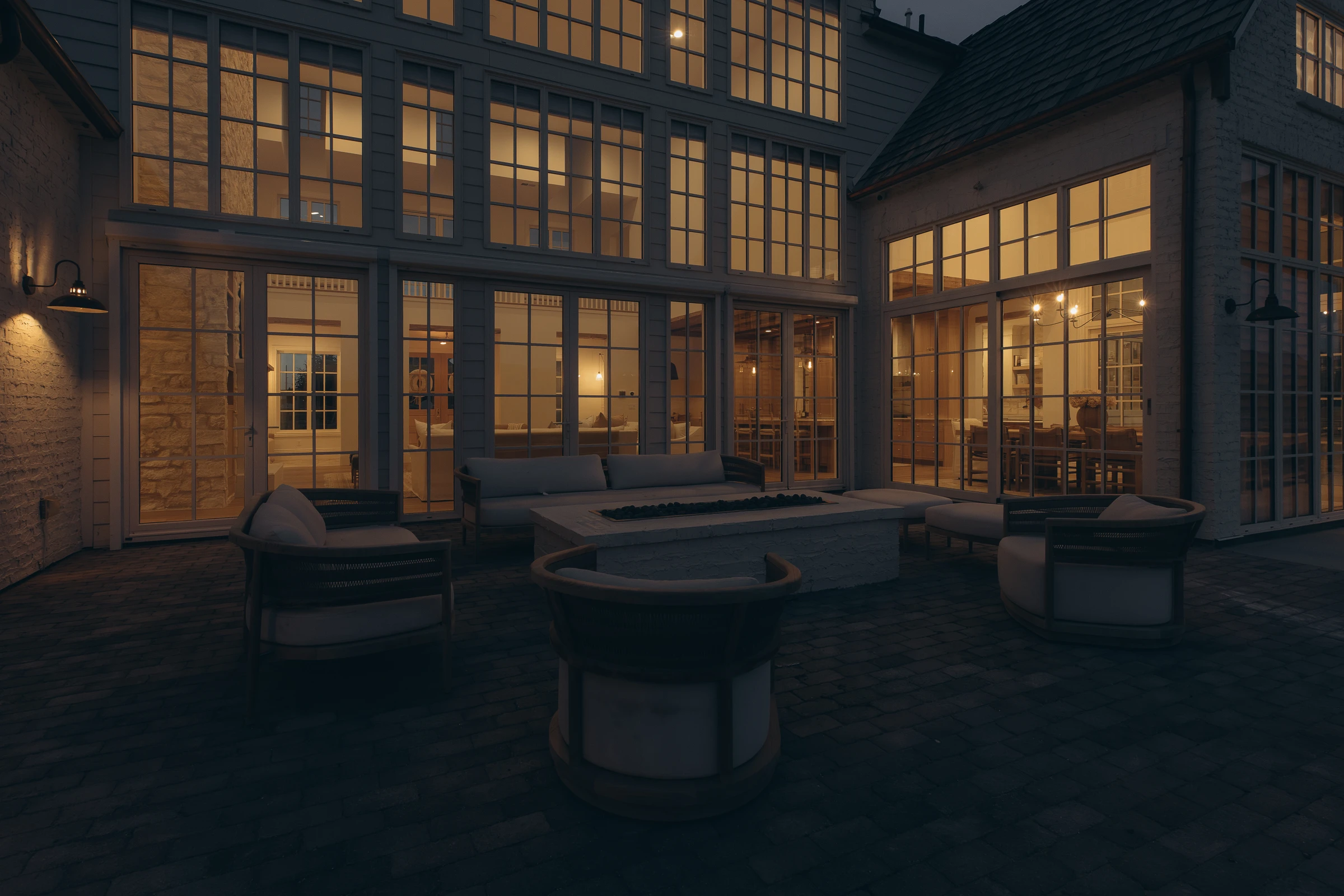 Night courtyard with linear fire table and three-story glowing window wall